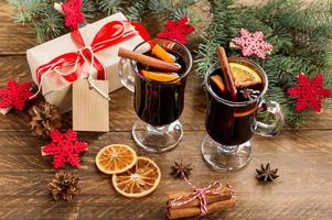 Christmas mulled red wine with spices and oranges on a wooden rustic table. Traditional hot drink at Christmas with gifts photo