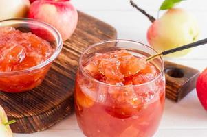 mermelada espesa con rodajas de manzana en un frasco y un tazón. postre vitamínico. foto