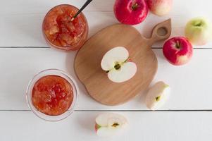 apple jam in a glass jar and half a ripe apple on an apple-shaped board. top view. the concept of healthy eating. photo