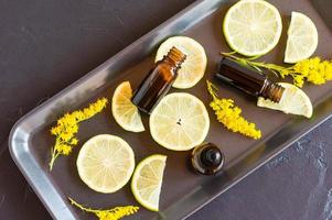 botellas de aceite esencial de cítricos sobre fondo negro y rodajas de fruta. aromaterapia, efecto antiestrés. foto
