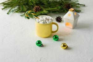 dirty Christmas chocolate or cocoa in a ceramic yellow mug with yogurt and caramel on a white background with spruce branches and a candle. photo