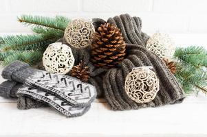 knitted warm scarf and mittens in the composition with openwork balls, cones and branches of spruce on a white background. the concept cozy Christmas. photo