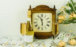 Christmas or New Year's composition with an old clock, a bottle of champagne, two boglass at the tree with toys and gifts. photo