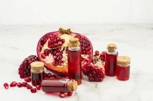 pomegranate oil in bottles on the background of the fruit of pomegranate for skin care. universal cosmetic, antioxidant. photo