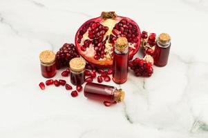 essential aromatic oil with pomegranate and fruit grains on a marble background. selective focus. photo