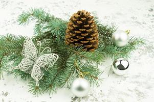 New Christmas composition with spruce branches, a large cedar cone, silver balls, openwork butterfly on a winter background. photo