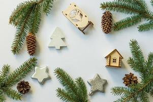 New Year's festive background with cones and green branches, silver stars, wooden sleds and a toy house. flat layout. top view. photo