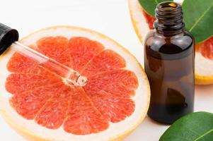 dropper with grapefruit oil on the fruit lobe. bottle with grapefruit oil. skin care, spa concept. photo