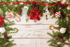 fondo de navidad con adornos navideños tradicionales: bolas de vidrio, bastón de caramelo, flor roja sobre un fondo blanco de madera. una copia del espacio. foto