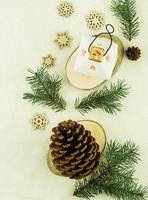 vertical New Year's knitted background. a large cedar cone, a burning candle in a candlestick, decorative wooden snowflakes and branches of the yel. photo