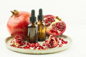 serum with vitamin C, with organic pomegranate essential oil on a plate with ripe pomegranate. the concept of natural skin care. photo