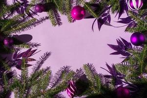 original Christmas lilac background with green spruce branches, purple balls and decorative leaves with glitter. a copy of the space. photo