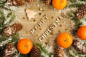 Christmas holiday background with the letters of Merry Christmas, citrus, spruce branches and cones. top view. burlap. photo