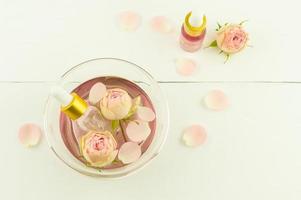 pink cosmetic water in a bowl with rose petals, dropper bottles with an extract of roses on a white background. top view. photo