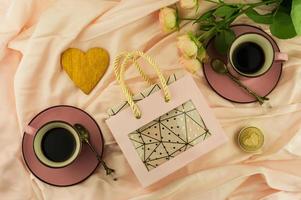 A gift with love. festive package with box,bouquet of roses,heart of gold and two cups of coffee. the concept of celebrating Valentine's Day. photo