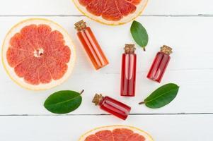 flat layout. top view. bottles with cork lid and grapefruit essential oil, sweets of juicy fruit. photo