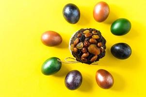 Easter cake with nuts and dried fruits on a yellow background with multi-colored colored eggs. the concept of the Easter holiday. top view. photo