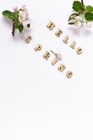 Hello spring-wooden letters on a white background with spring flowers and apple buds. Vertical background. a copy of the space. photo