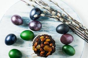 Easter cake with dried fruits and chocolate on a pastel background with colored eggs and willow twigs. top view. photo