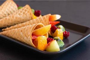 ripe sliced fruit in waffle cones on a plate. delicious dessert. photo