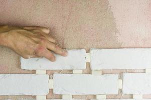 the employee's hand presses the decorative tiles against the finishing wall on the mortar. tile laying technology. photo