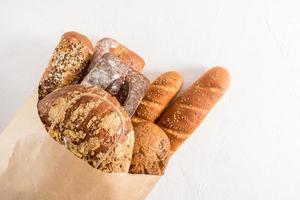 bolsa kraft rellena con varios tipos de pan de la panadería. cero desperdicio, compras ecológicas y entrega. Fondo blanco. foto