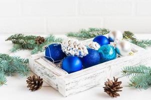 Christmas decorations in a wooden box on a white table with spruce branches and cones. the concept of a new year and Christmas. photo