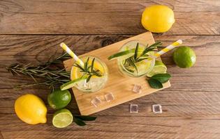 summer cold drinks with sliced citrus and sparkling water in two glasses on a wooden table. top view. rustic style. photo