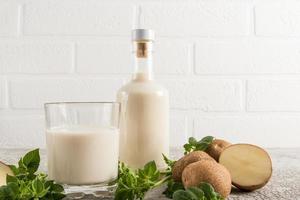 Vegan vegetable milk from potatoes is a new trend in food . glass bottle of milk opposite a white brick wall . photo