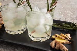 two glasses with a soft drink, homemade lemonade with ginger. close angle. gray background. photo