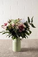 a bouquet of freshly cut garden flowers in a modern vase stands on a table with a text card. the end of the gift, the attention of loved ones. photo