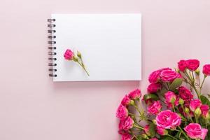 the top view of the white leaves of the boknot with a rosebud and a beautiful bouquet of flowers. pink background. a copy of the space. photo