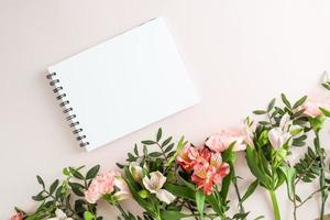 a blank notebook with white sheets on a black spring on a pastel background with spring flowers. top view. a copy of the space. photo