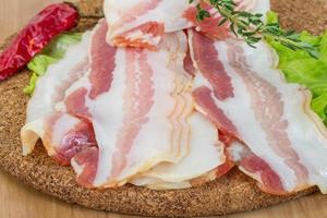 Bacon on wooden board and wooden background photo