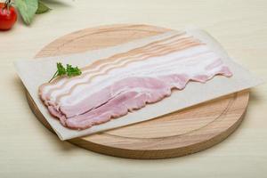 Raw Bacon on wooden board and wooden background photo