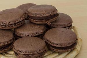 Chocolate macaroons on wooden board and wooden background photo