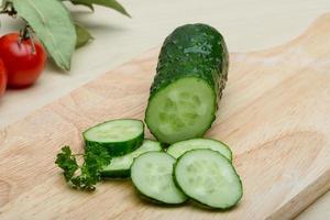 Sliced cucumber on wooden board and wooden background photo