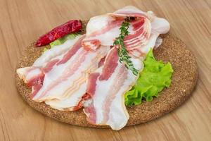 Bacon on wooden board and wooden background photo