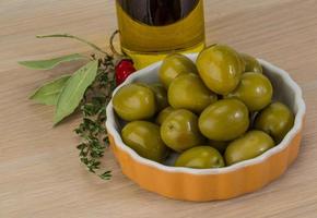 Green olives in a bowl on wooden background photo