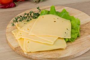 Sliced cheddar on wooden board and wooden background photo