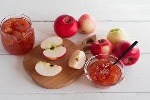 manzanas rojas maduras frescas en una tabla de cortar. jalea de manzana dulce o mermelada en un arco de vidrio. postre para una alimentación saludable foto