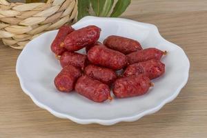 Mini salami on the plate and wooden background photo