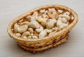 nueces de cajú en una canasta sobre fondo de madera foto