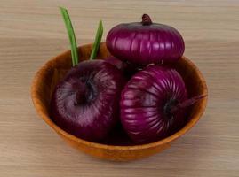 cebolla violeta en un bol sobre fondo de madera foto