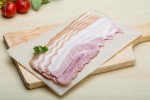 Raw Bacon on wooden board and wooden background photo