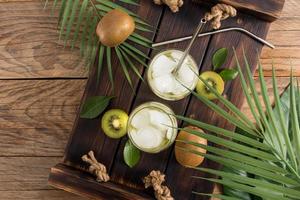 Top view of a wooden tray with two glasses of organic vitamin water from fruit with ice pieces. a refreshing drink. detox menu. photo