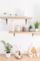 Front view of modern kitchen open shelves with jars for storing food and potted houseplants. part of the countertop with kitchen utensils. photo