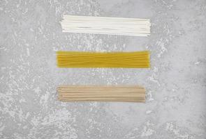 three types of dry Italian paste on a gray concrete background. noodles, spaghetti, buckwheat noodles. top view. photo