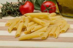 Raw penne on wooden board photo