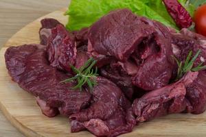 Raw venison on wooden board and wooden background photo